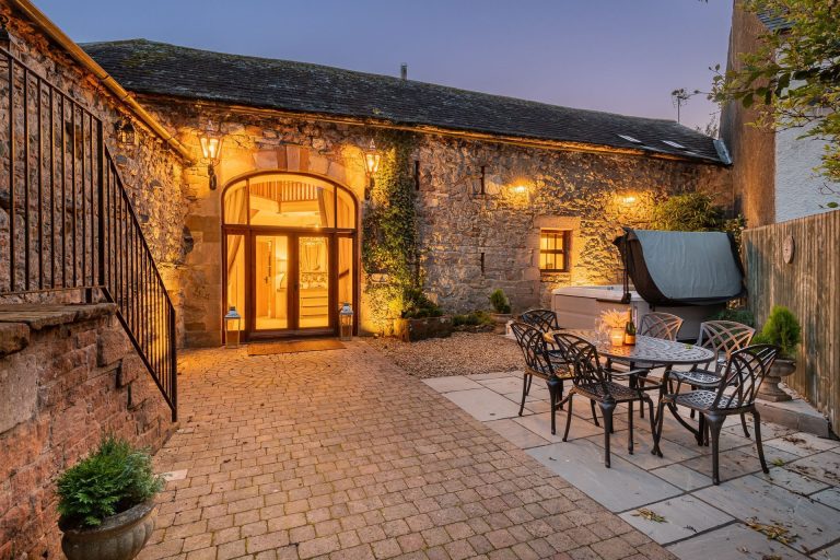 Courtyard garden lit up at night at Rose Walls cottage