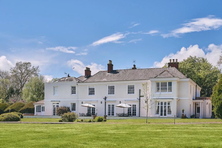 White washed manor house with lawned garden in the foreground